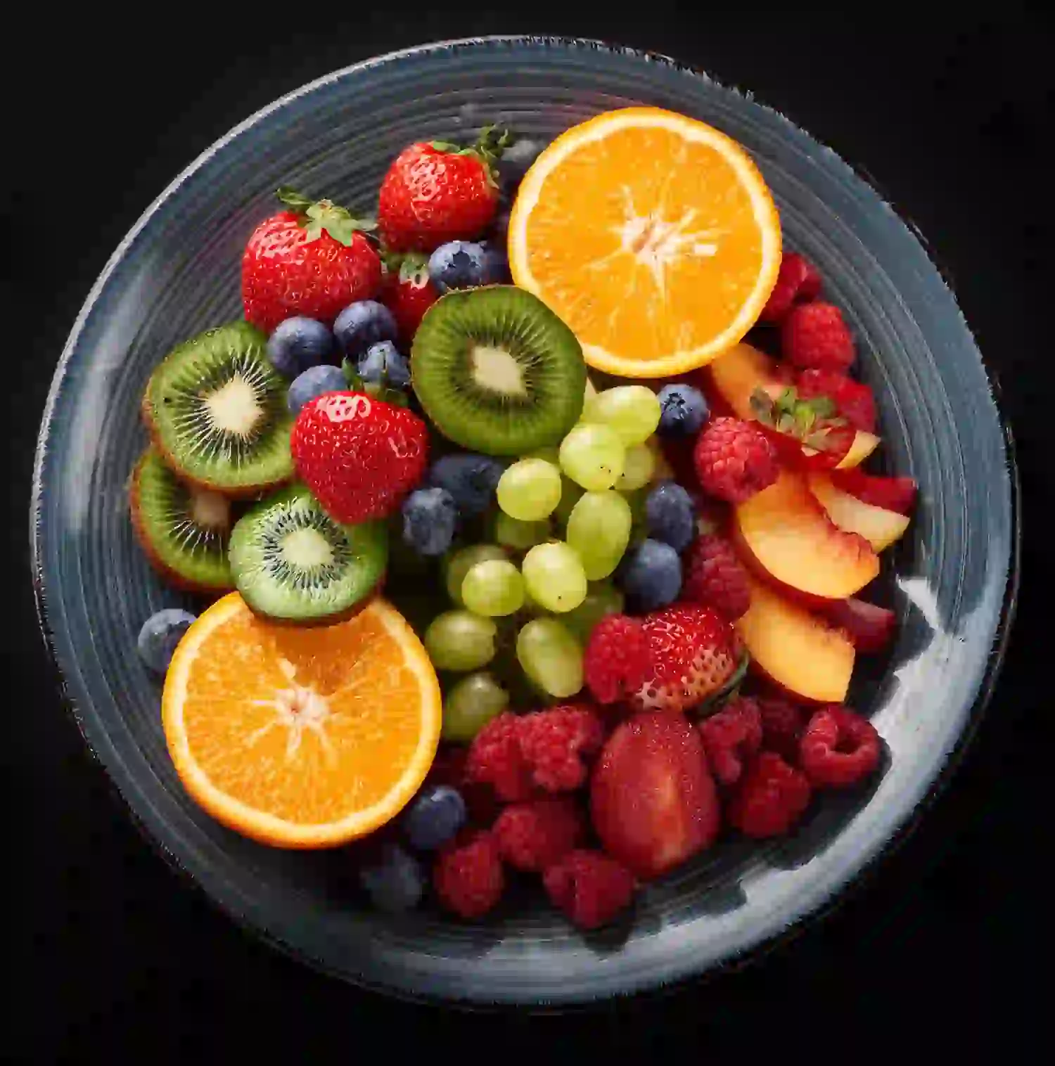 Ein blauer Teller gefüllt mit geschnittenen Orangen, Kiwis, Erdbeeren, Weintrauben, Blaubeeren, Himbeeren und Pfirsichscheiben ähnelt einem unserer Verwöhnpakete, alles ordentlich auf einem schwarzen Hintergrund angerichtet.